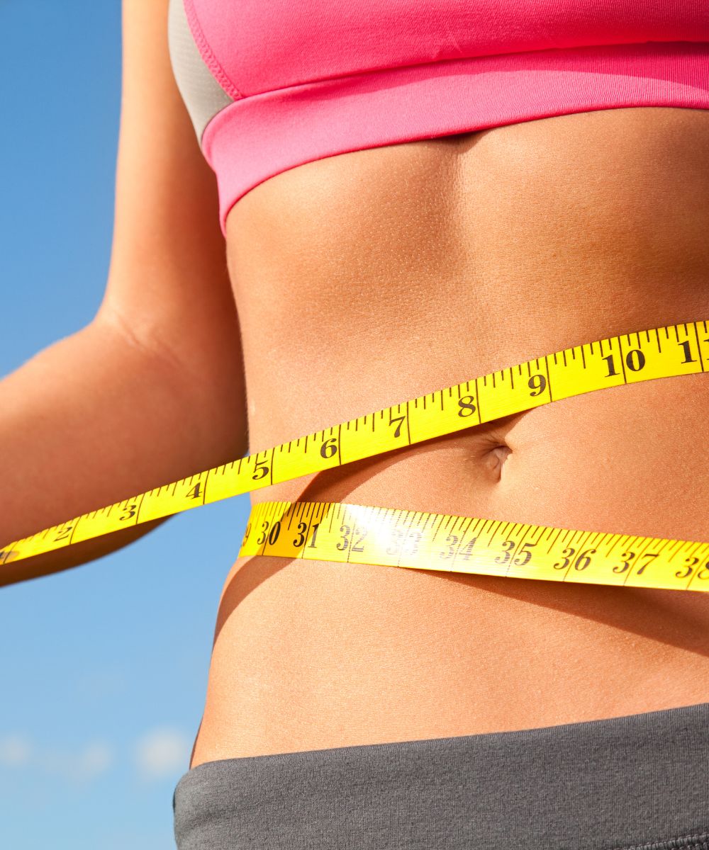 Measuring tape around woman's waist, fitness concept.